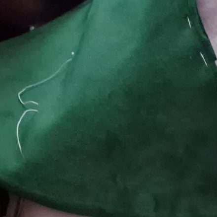 Pannello in tessuto verde imbastito a mano, con il filo di imbastitura ancora in vista